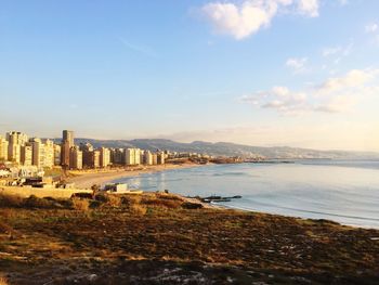 Scenic view of sea by cityscape against sky