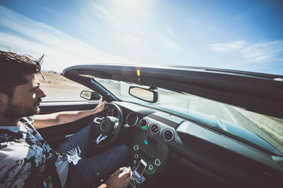 Portrait of man on car against sky