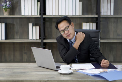 Young man using mobile phone while sitting on table