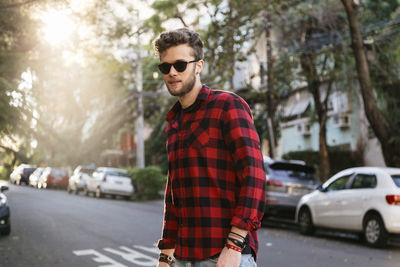 Man wearing plaid shirt and sunglasses while walking on road