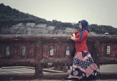 Full length of young woman standing against sky