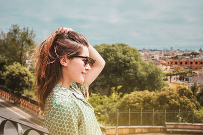 Profile portrait of young smiling woman in sunglasses with a panoramic view of rome, italy