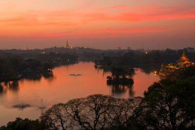 Scenic view of river by buildings against sky during sunset