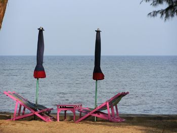 Deck chairs on beach against clear sky