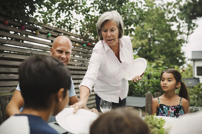 Senior woman giving plate to grandson at outdoor dining table