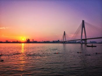 View of suspension bridge over sea during sunset