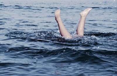 Low section of child swimming in sea