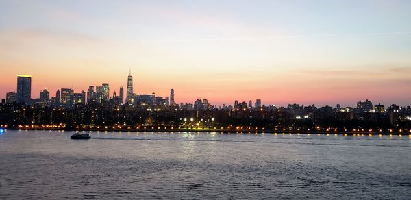 Illuminated buildings in city against sky during sunset