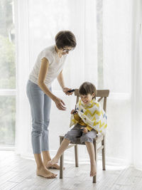 Woman giving haircut to son at home