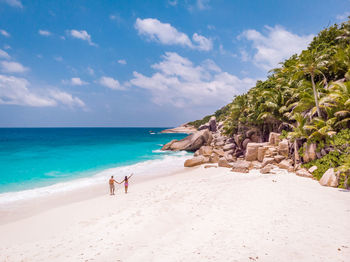 Rear view of couple walking on shore at beach