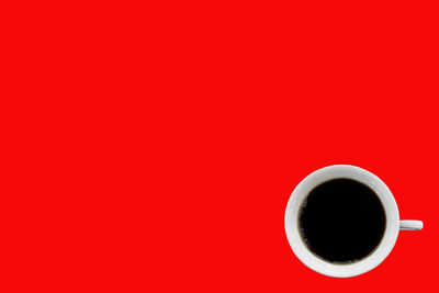 Directly above shot of coffee cup against red background