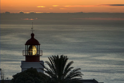 Silhouette built structure by sea against sky during sunset