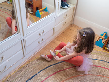 High angle view of girl wearing shoe at home