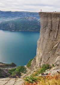 Girl standing on cliff by sea against sky