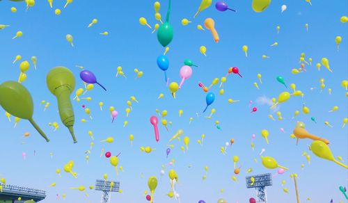 Low angle view of balloons flying against blue sky