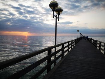 Pier over sea against sky during sunset