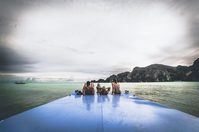 People relaxing in swimming pool by sea against sky