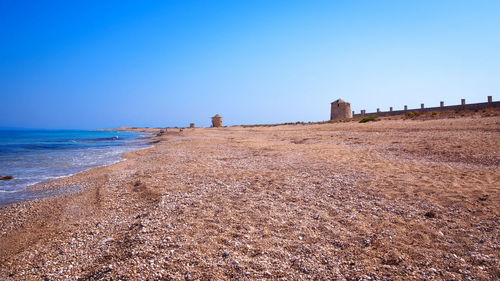 Scenic view of beach against clear blue sky