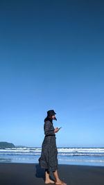 Full length of girl on beach against clear blue sky