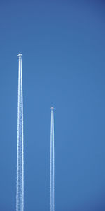 Low angle view of airplane flying against clear blue sky