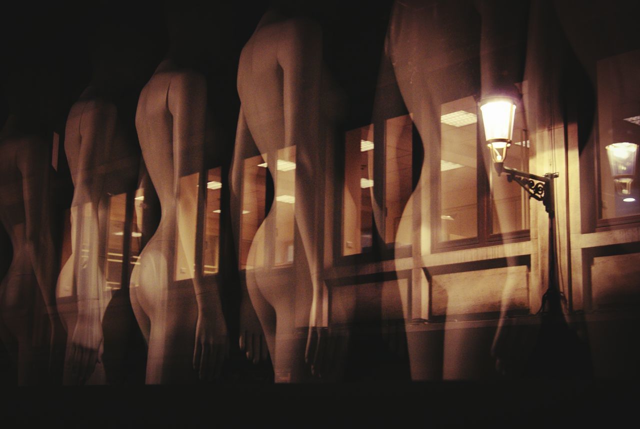 MULTIPLE EXPOSURE OF PEOPLE IN ILLUMINATED CORRIDOR