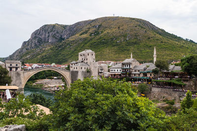 Arch bridge by buildings against sky