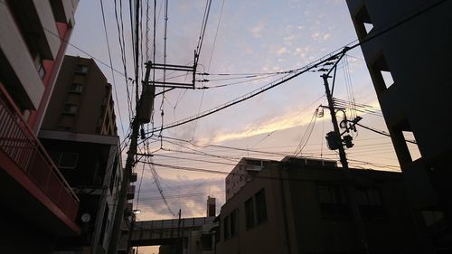 Low angle view of electricity pylon and buildings against sky