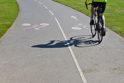 Shadow of man riding bicycle on road