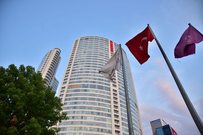 Low angle view of flags and buildings against blue sky
