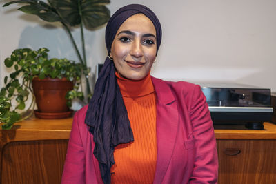 Portrait of young woman standing against wall