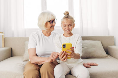 Young woman using phone while sitting on sofa at home