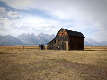 Barn on field by mountains against sky