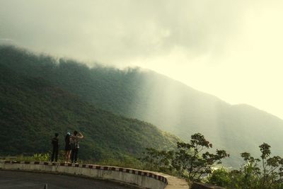 People standing on mountain road against sky