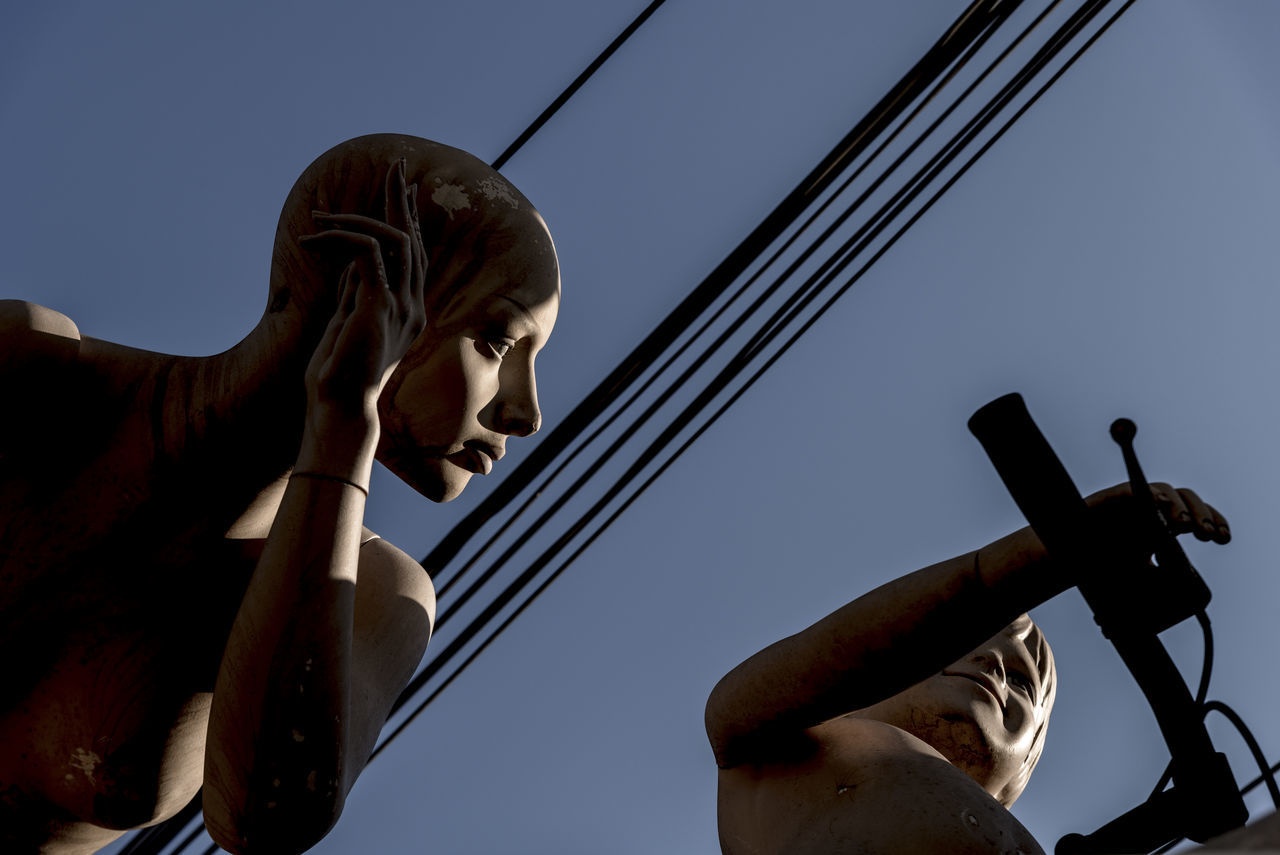 sky, low angle view, clear sky, nature, human representation, sculpture, representation, art and craft, human body part, day, statue, male likeness, creativity, one person, human hand, outdoors, real people, body part