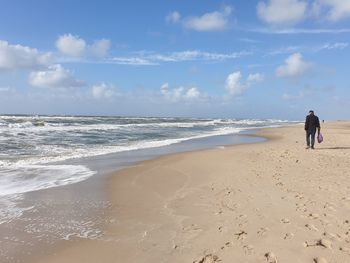 Rear view of people on beach against sky