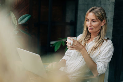 Young attractive business woman sitting in a coworking space working on a laptop.