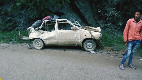 Side view of man on car against trees