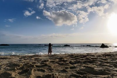 Man standing on beach against sky during sunset