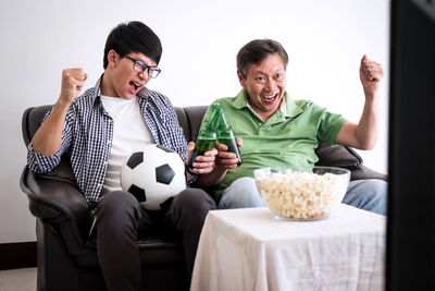 Family with food and drink watching sports on tv at home