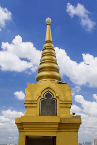 Low angle view of gold stupas against sky