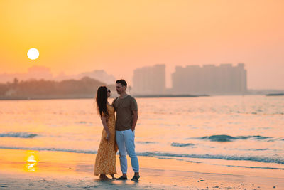 Couple standing on beach during sunset