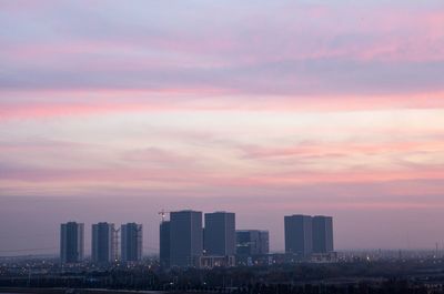 Modern cityscape against sky during sunset