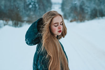 Portrait of young woman standing against snow