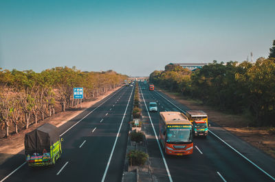 Vehicles on road against clear sky