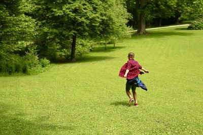 Full length of boy running on grassy field
