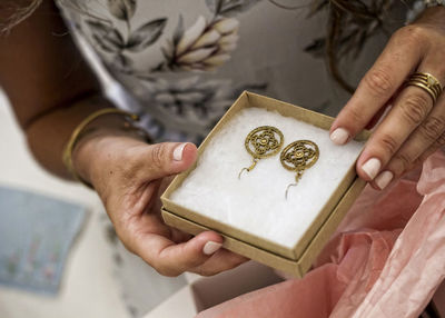 Midsection of woman holding earrings