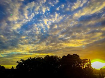 Low angle view of silhouette trees against cloudy sky