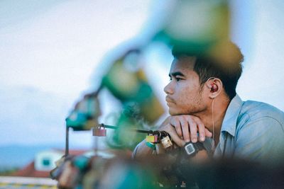 Side view of thoughtful young man leaning on railing 