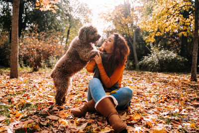 Full length of young woman sitting on street during autumn