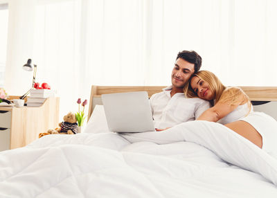 Man and woman using mobile phone while relaxing on bed